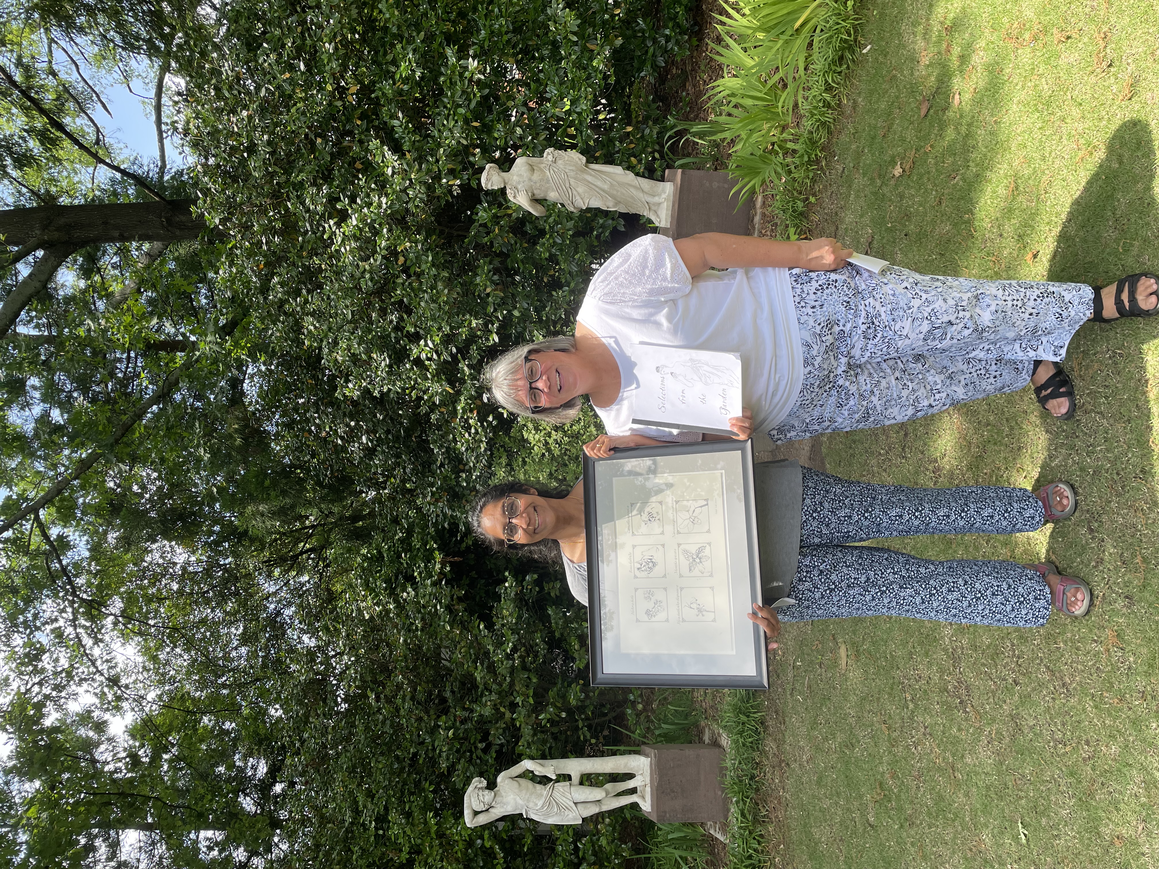 Dr. Iyengar and Dr. Goetchus display the Osiris’ group’s large, framed, botanical digital art print and accompanying booklet with references to the plants from early literature.